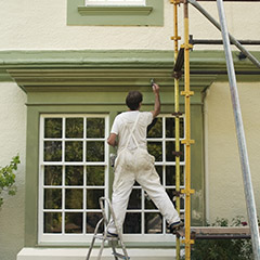 Team members painting exterior of home