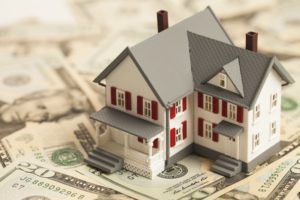 a model house sitting on a table of money