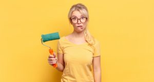 woman holding a roller and looking confused about paint gloss