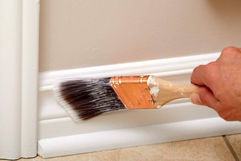 closeup of man painting interior trim 